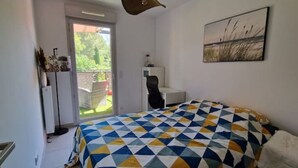 Een slaapkamer met een bedovertrek met een geometrisch patroon, een stoel, een bureau en een schilderij aan de muur.