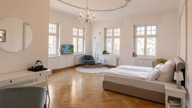 Ein geräumiges Schlafzimmer mit einem großen Bett, einem Schreibtisch, einem Stuhl und einem Fernseher.