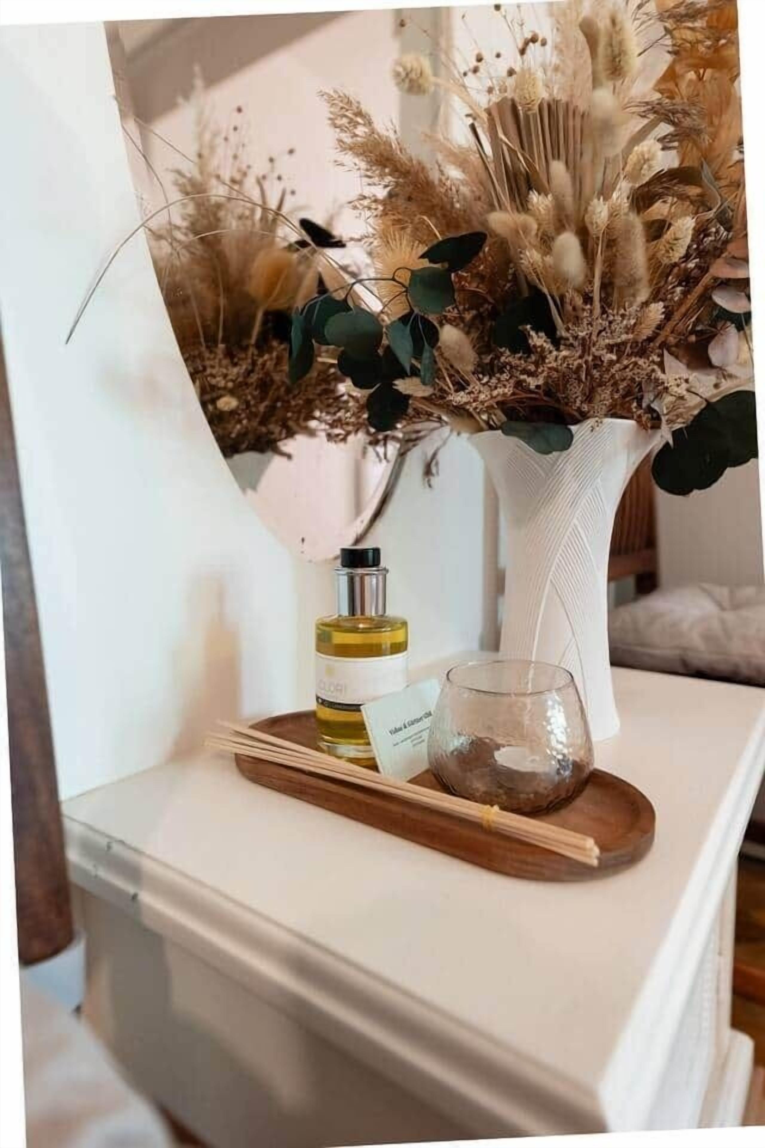 Uma mesa de cabeceira branca com um copo, uma garrafa e um descanso com pauzinhos.