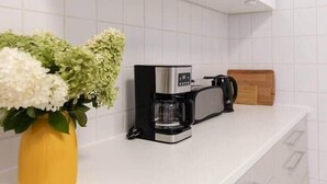 Eine Küche mit weißen Fliesen, einer Kaffeemaschine und einem Holztisch.