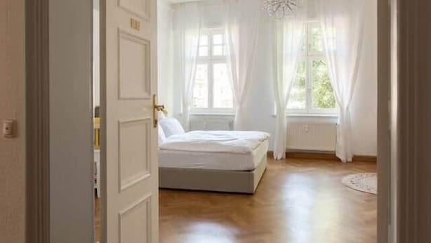 Ein Zimmer mit einem Bett, einem Deckenventilator und einem Fenster mit Vorhängen.