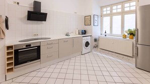 A modern kitchen with a built-in oven, microwave, and washing machine, a window with a view, and a refrigerator. - Twinbed (Stendal)