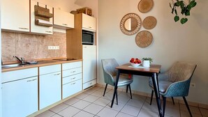 A modern kitchen with white cabinets, a wooden countertop, and a hanging light fixture. - Altstadt Studio - Hygge im Hoock (Stendal)
