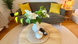 A round wooden coffee table with a white vase and a remote control on a woven placemat. - Altstadt Studio - Hygge im Hoock (Stendal)