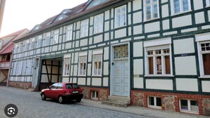 A traditional half-timbered building with a red car parked in front. - Altstadt Studio - Hygge im Hoock (Stendal)