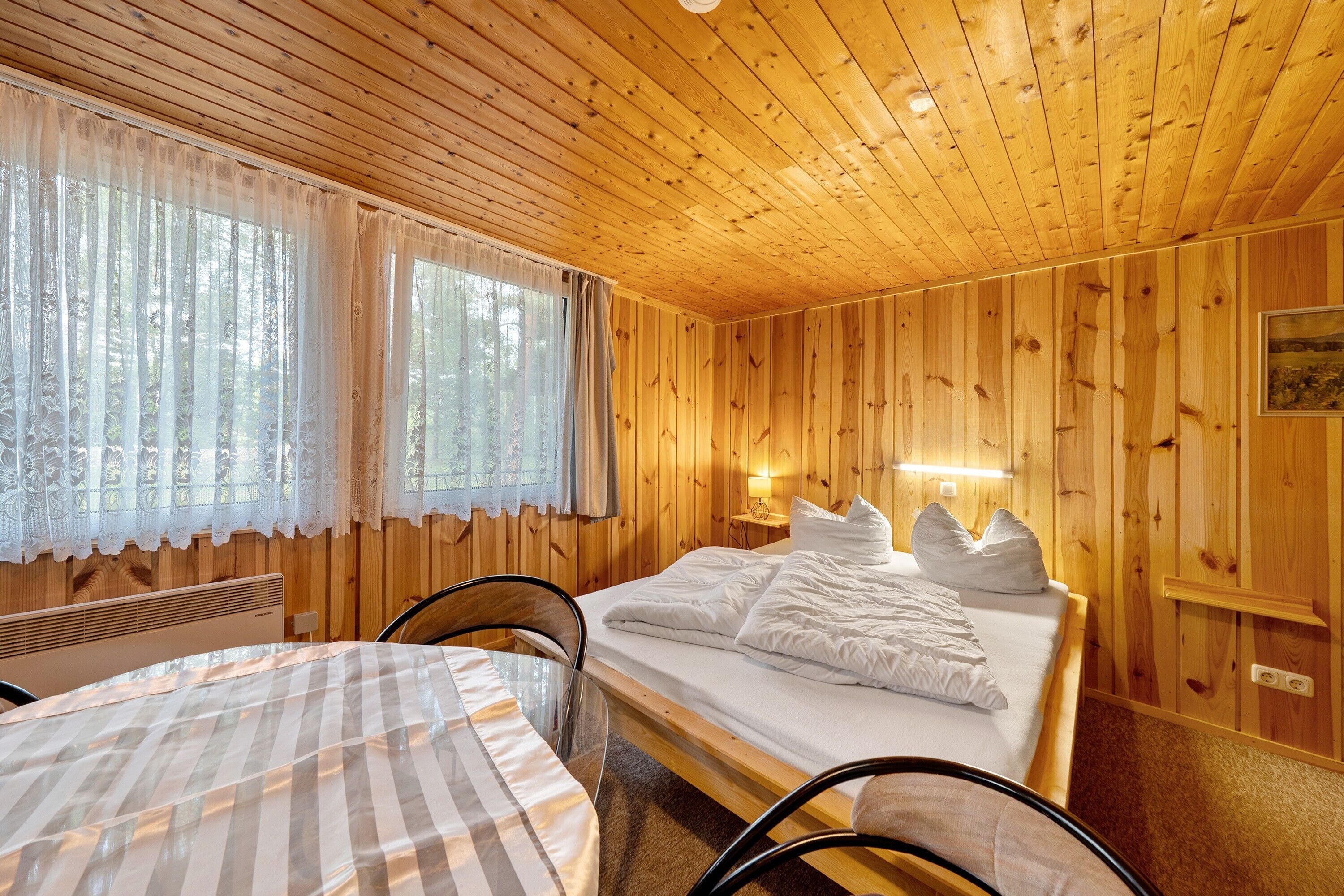 Una stanza con rivestimenti in legno, un letto, un tavolo e sedie.