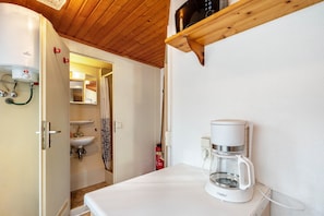 Une salle de bain avec des toilettes, un lavabo et une douche. Il y a une machine à café sur le comptoir.