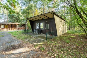 Une cabane avec une véranda, une table et une chaise.