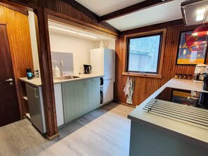 A compact kitchen with wooden accents, a built-in sink, and a window providing a view of the outdoors. - 4 Star Holiday Home in Ry (Ry)