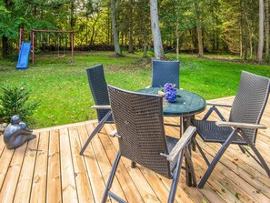 A wooden deck with a table and chairs, surrounded by a grassy area and trees. - 4 Star Holiday Home in Ry (Ry)