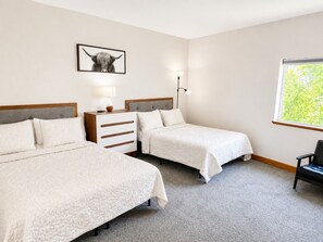Habitación de hotel con dos camas, una mesita de noche, una lámpara y un cuadro en la pared.