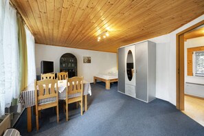 Une pièce avec un plafond en bois, une table à manger avec des chaises, un lit, une armoire et une fenêtre avec des stores.
