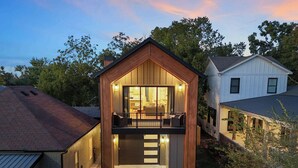 Une maison moderne avec une façade en bois, un balcon et un intérieur bien éclairé.