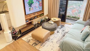 A modern living room with a flat-screen TV, a sofa, a coffee table, and a balcony with a view. - Armin Homes Corner 3 BRs with bathtub (Phung Cong)