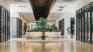 A modern hotel lobby with a central planter, glass doors, and a polished floor. - Armin Homes Corner 3 BRs with bathtub (Phung Cong)