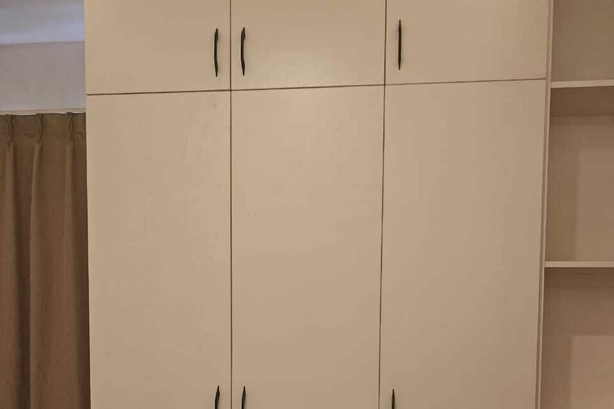 A wardrobe with two doors and a lower shelf, featuring a light upper section and a darker lower section.