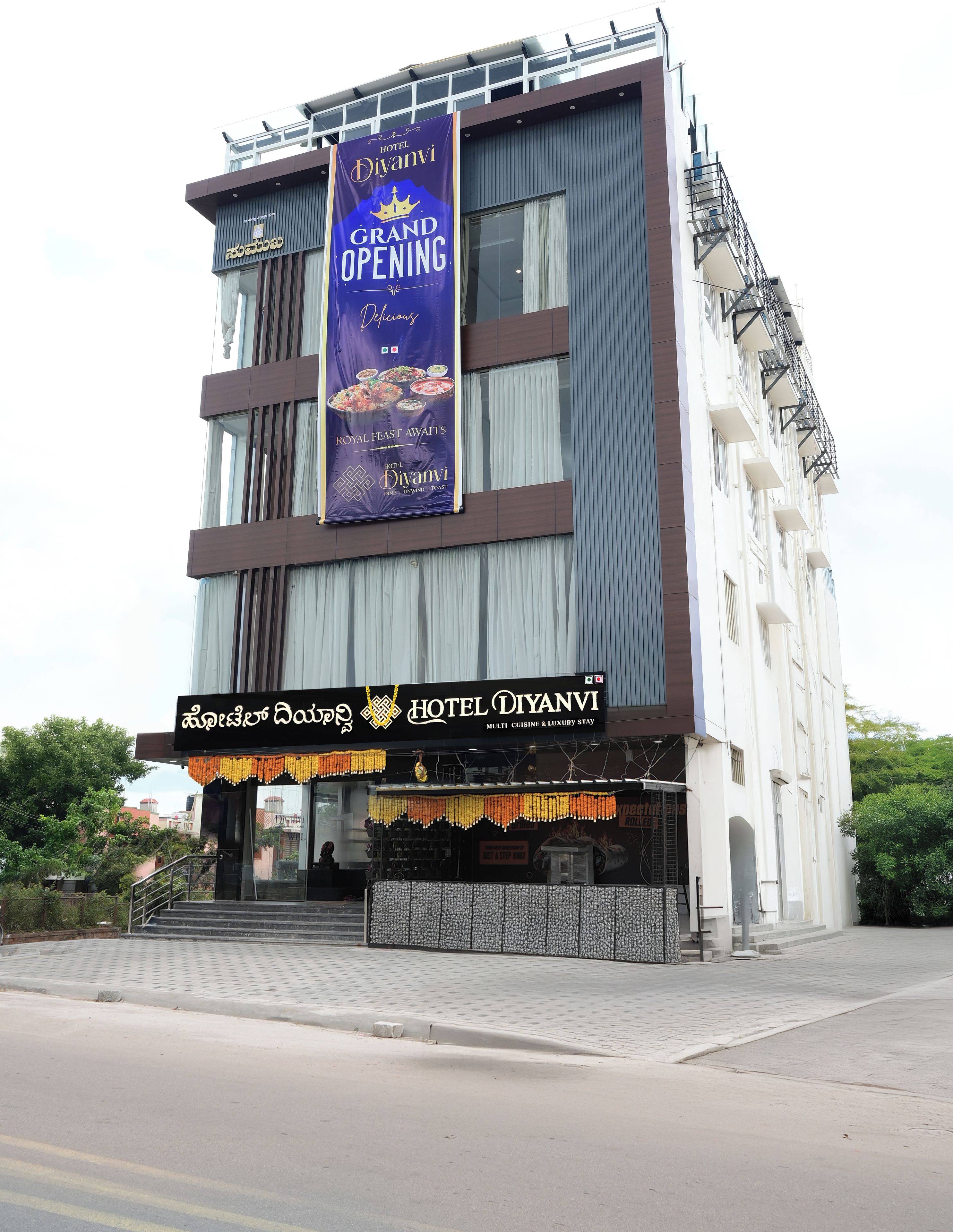 Hotel Diyani, met een groot openingsbanner, toont een moderne gevel met een balkon en een naambord in een lokale taal.