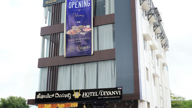 A hotel named Hotel Diyani with a grand opening banner, featuring a modern facade with a balcony and a signboard in a local language. - Hotel Diyanvi (Mysore)
