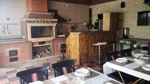 A kitchen with a brick oven, wooden bar, and dining area with chairs and tables. - Guest House Discovery (Almaty)