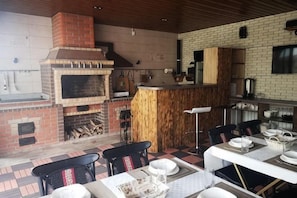A kitchen with a brick oven, wooden bar, and dining area with chairs and tables. - Guest House Discovery (Almaty)