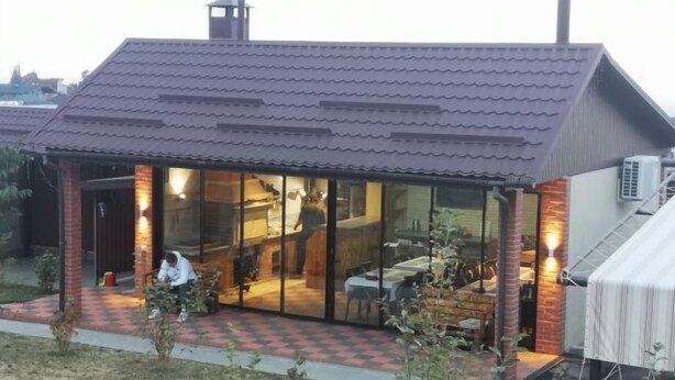 A small, modern house with a tiled roof, large glass windows, and a brick exterior. - Guest House Discovery (Almaty)