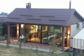 A house with a covered patio, a brick exterior, and a visible interior with a dining area. - Guest House Discovery (Almaty)