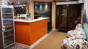 A reception area with a modern design, including a reception desk, a refrigerator, and a seating area with patterned cushions. - Guest House Discovery (Almaty)