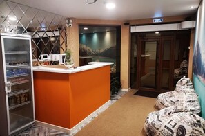A reception area with a reception desk, a refrigerator with beverages, and a door leading to another room. - Guest House Discovery (Almaty)