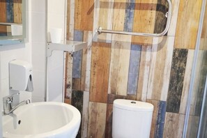Une salle de bain avec un lavabo blanc, des toilettes et une barre d’appui.