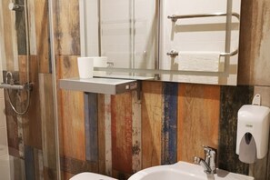 Une salle de bain avec un mur recouvert de panneaux en bois, un lavabo blanc, un miroir, un porte-serviettes et un distributeur de savon.