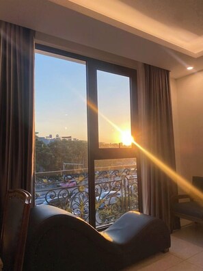 A room with a large window, a view of the cityscape, and a sofa. - Victory Hotel Ha Noi (Hanoi)