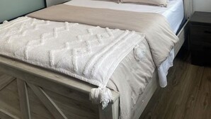 A neatly made bed with a wooden headboard, a white throw blanket, and two pillows. - Waterfront tiny home with hot tub (Pet friendly, near beaches) (Richibucto-Village)