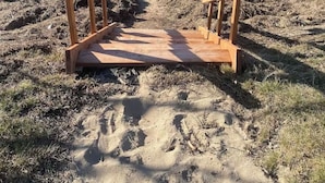 A wooden bench with a caution sign in front of a lake. - Waterfront tiny home with hot tub (Pet friendly, near beaches) (Richibucto-Village)