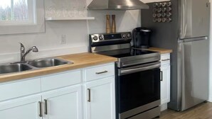 A modern kitchen with white cabinets, a stainless steel range, a built-in oven, a double sink, and a refrigerator.