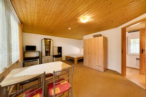 A room with a wooden ceiling, a bed, a wardrobe, a table with chairs, and a television. - Bungalow '25 - Kimbucht' with Private Terrace and Shared Garden (Waldhufen)