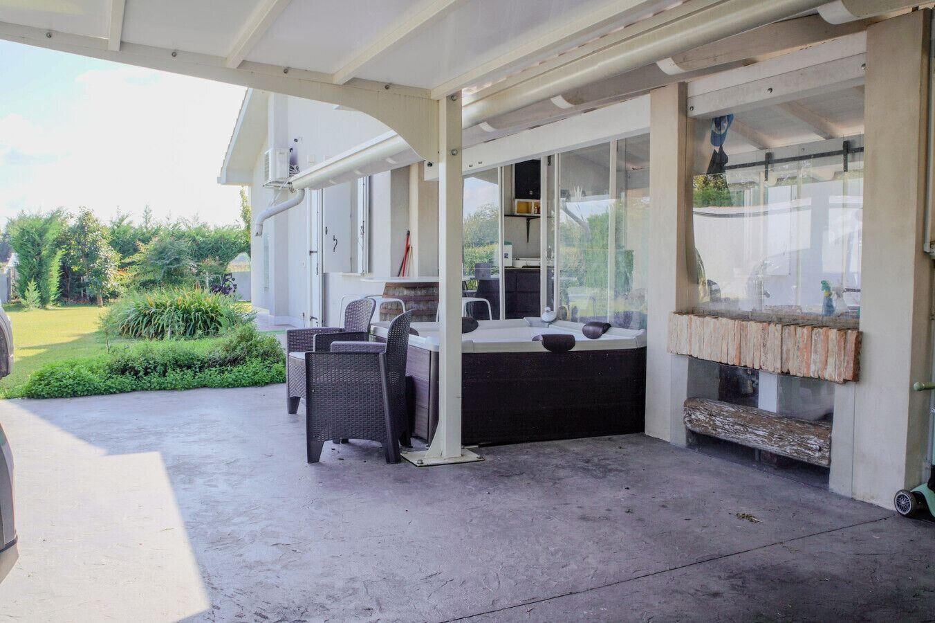 Un patio exterior con área de estar techada, un jacuzzi y una rústica chimenea de ladrillo.