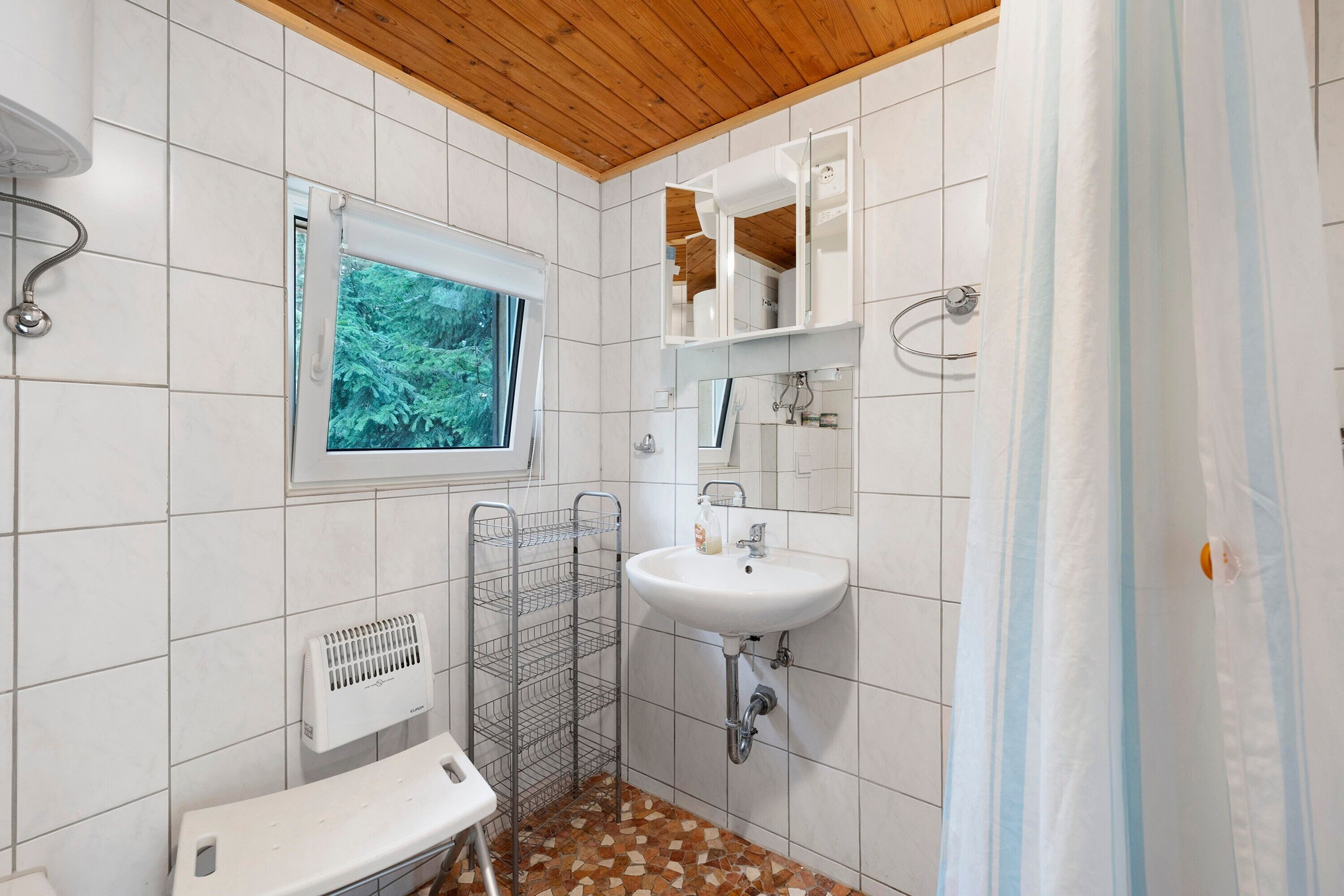 A bathroom with a window, a sink, a mirror, and a shower curtain.