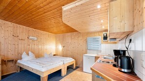 A wooden cabin with a bed, a small kitchenette, and a window.