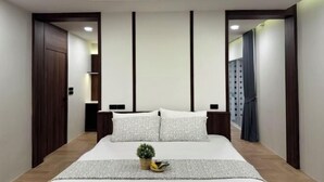 Quarto moderno com uma cama grande, uma mesinha de cabeceira e um criado-mudo.