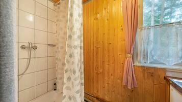 Ein Badezimmer mit Dusche, einer Holzwand und einem Fenster mit Blick auf Bäume.