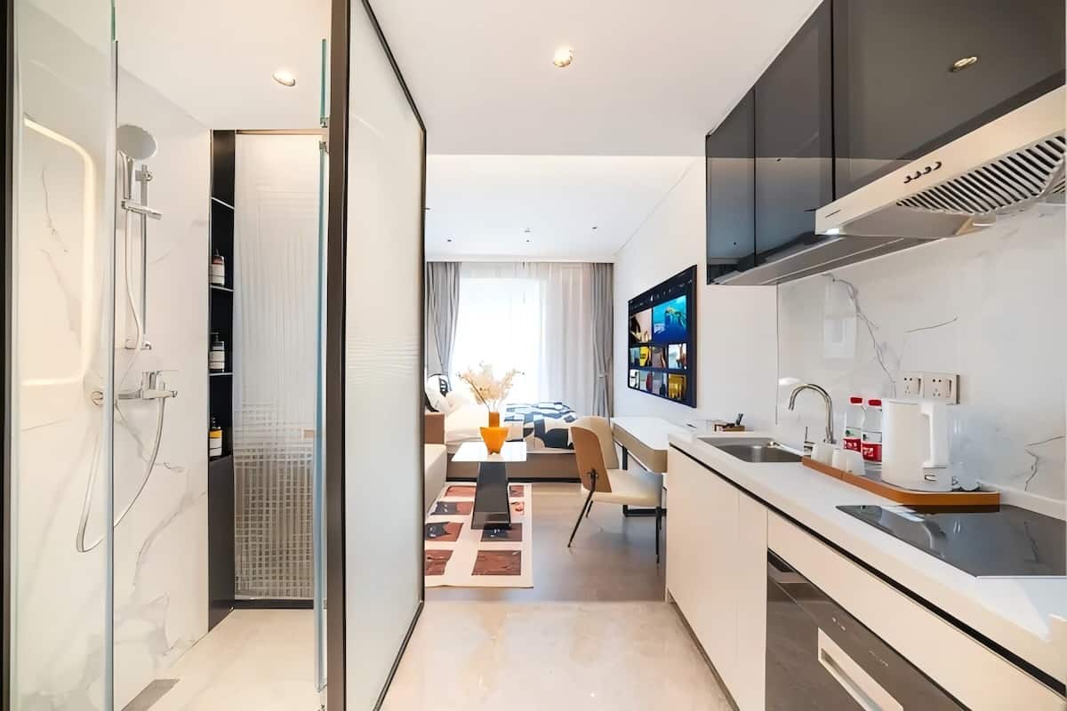 A modern kitchen with a built-in stove, a large window, and a dining area with a sofa and table.