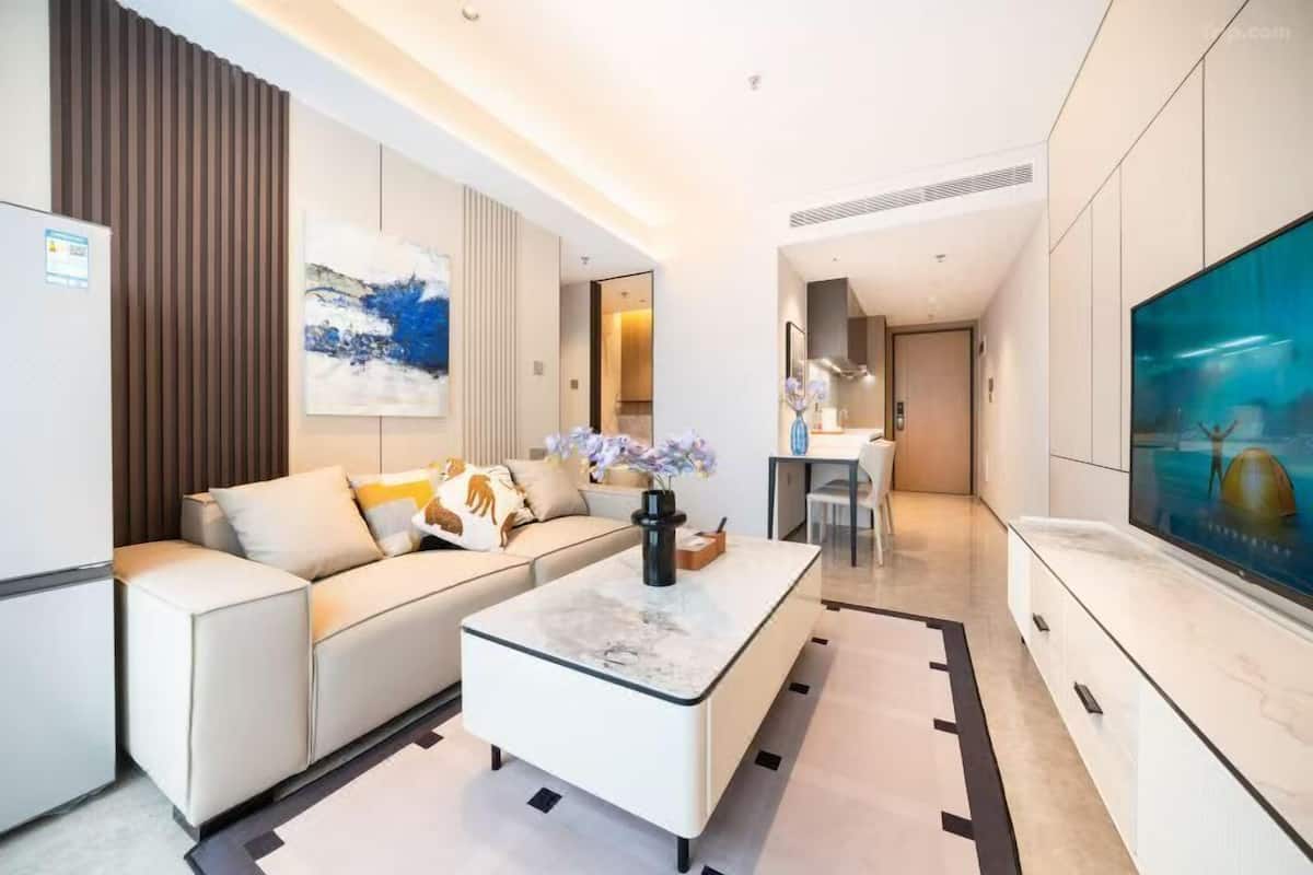 A modern living room with a sofa, coffee table, and a large TV.