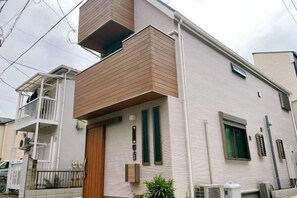 A two-story residential building with a wooden front door, a balcony, and a small attached garage. - Oku Station;4 Minutes Walk from Station;Ueno 5 Minutes; Tokyo 12Minutes; Shinbashi (Ginza) 15Minutes (Tokyo)