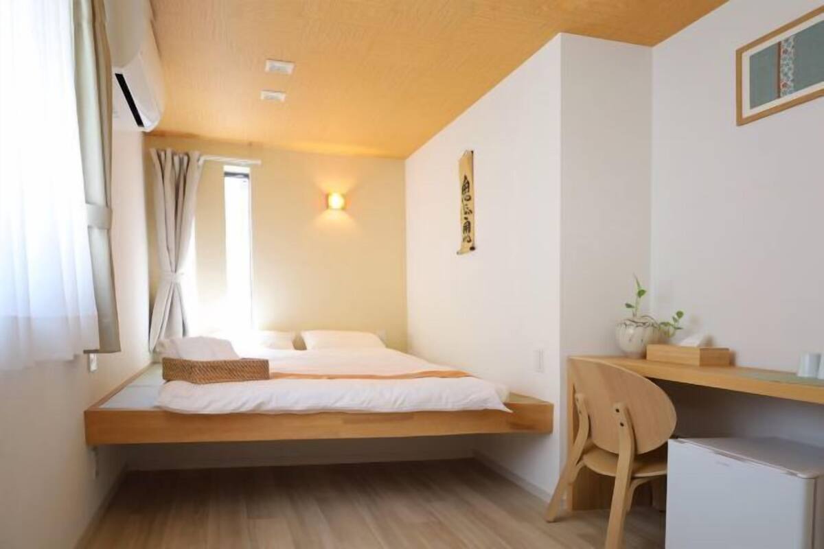 Ein kleines Zimmer mit Bett, Schreibtisch und Stuhl.