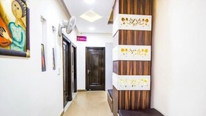 A hallway with a wooden accent wall, a black door, and a ceiling fan. - PRINCE RESIDENCY (Amritsar)