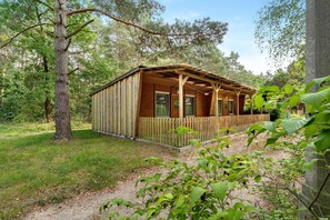 A wooden cabin with a porch, surrounded by trees.