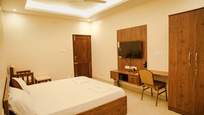 Une chambre à coucher comprenant un lit, un bureau, une chaise, un téléviseur fixé au mur et des armoires en bois.