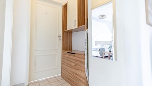 A hallway with a white door, wooden cabinets, and a refrigerator.