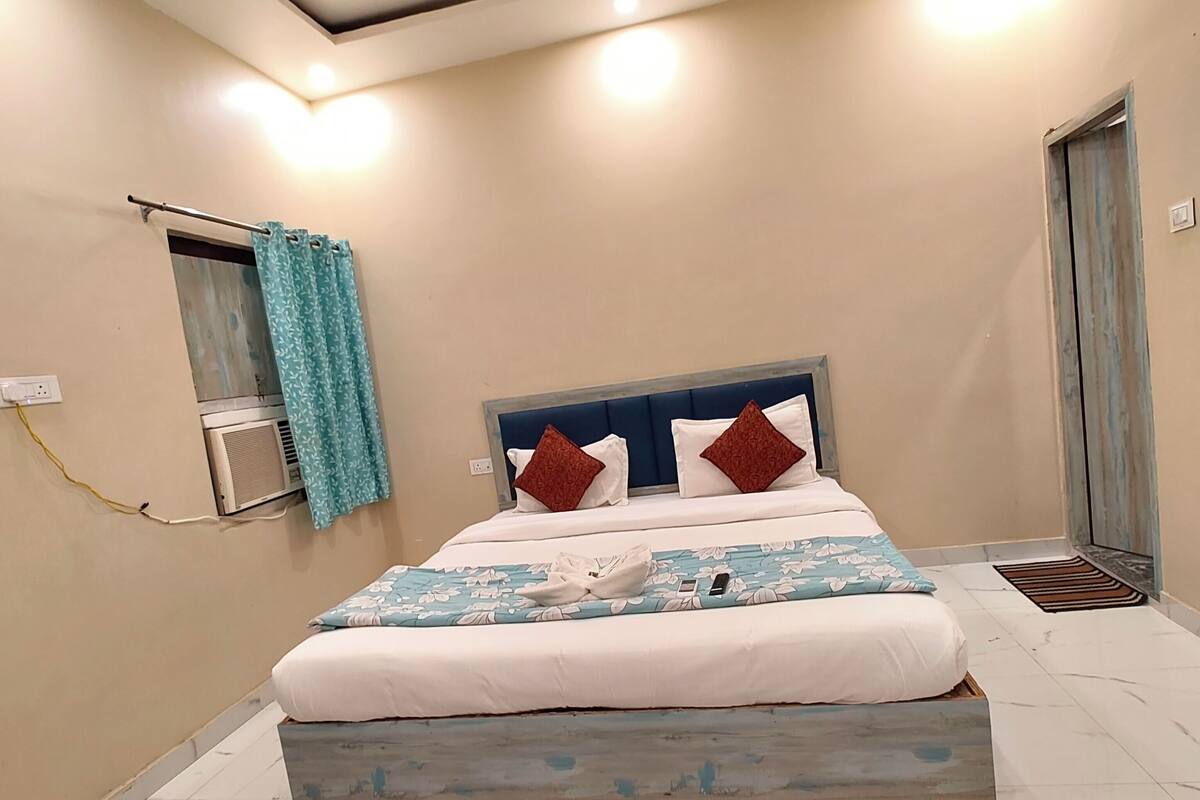 Un dormitorio con cama, ventilador de techo, aire acondicionado y puerta al baño.