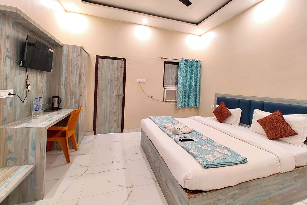 Un dormitorio con cama, escritorio, televisor y ventilador de techo.